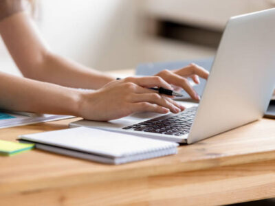 Cropped close up image woman hands holding pen typing on laptop student do homework prepare essay make research, businesswoman communicate online with client solve business questions distantly concept